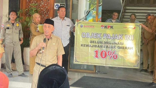 Pj Bupati Bangkalan Arief Mulya Edie Saat Menunjukkan Banner Peringatan Pada Rumah Makan Di Pendopo.