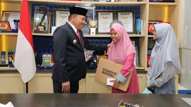 Bupati Sampang H. Slamet Junaidi Saat Memberikan Bantuan Biaya Pendidikan Dan Laptop Kepada Nuktatil Amirah.