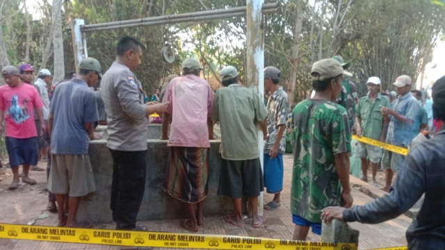 Petugas Kepolisian Dari Polsek Tragah Bersama Warga Berupaya Mengangkat Jasad Korban Dari Dalam Sumur.