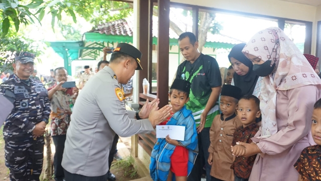 Personel Polres Bangkalan Saat Menyerahkan Santunan Pada Anak Yatim Piatu.